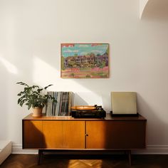 a record player sitting on top of a wooden cabinet next to a potted plant