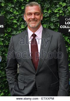 a man wearing a suit and tie standing in front of a green wall