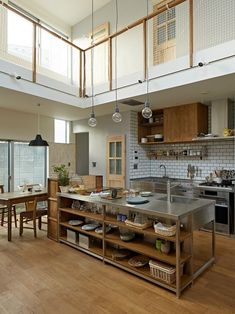 an open kitchen and dining area with wooden flooring, stainless steel counter tops and island