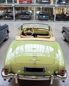 an old green car is parked in a showroom