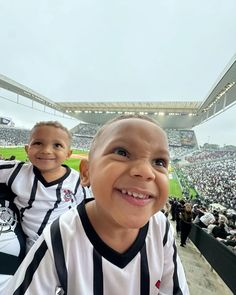 two young boys are sitting in the stands at a baseball game, one is wearing a black and white striped shirt