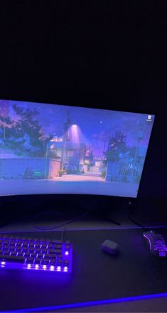 a computer monitor with a game on the screen and keyboard in front of it at night