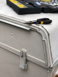 a pair of pliers sitting on top of a piece of luggage with other items in the background