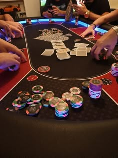 people playing cards at a casino table with their hands on the poker chips and cups