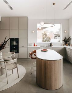 a modern kitchen with an island in the middle and two chairs around it, along with a dining table