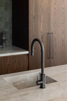 a kitchen sink sitting under a faucet next to a counter top in front of wooden cabinets