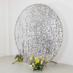 a large metal object sitting on top of a white floor next to yellow and white flowers