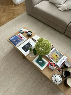 a living room with a couch, coffee table and pictures on the floor in front of it