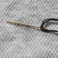 a knitting needle with black thread on a gray fabric