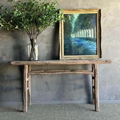 there is a painting on the wall next to a table with flowers and a vase