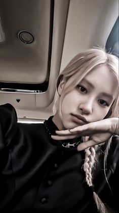 a woman with blonde hair wearing a black shirt and braids on her head sitting in an airplane