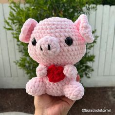 a small pink crocheted pig with a red heart