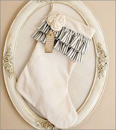 a christmas stocking hanging on the wall in front of a white frame with an ornament