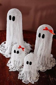 three white ghost decorations sitting on top of a wooden table