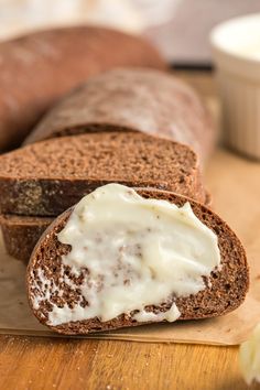 there is a loaf of bread with cream on it and another piece of bread in the background