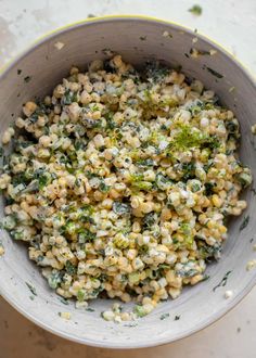 a white bowl filled with corn and broccoli on top of a marble table