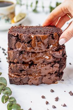 a person placing chocolate frosting on top of a brownie in front of some succulents