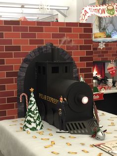 a black train engine sitting on top of a table next to a red brick wall