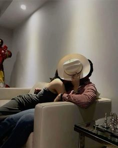 a man sitting on top of a couch next to a woman wearing a cowboy hat