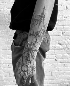 black and white photo of a man's arm with vines on it, in front of a brick wall