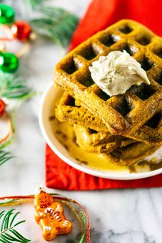 two waffles on a plate with whipped cream and christmas decorations in the background