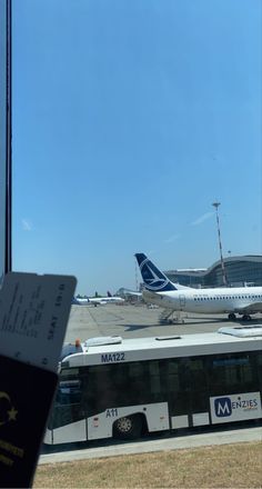 an airport with two buses parked on the tarmac and one passenger jet in the background