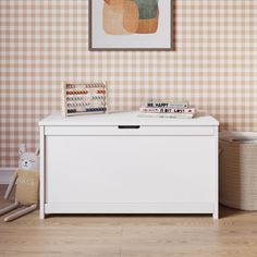 a white toy chest sitting in the corner of a room with checkered wallpaper