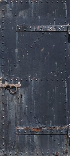 an old metal door with rust and rivets