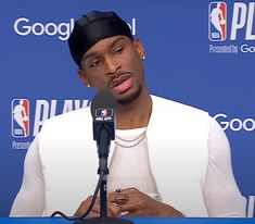 a man sitting at a microphone in front of a blue wall with the philadelphia 76 logo on it