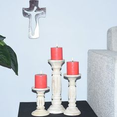 three candles sit on a table next to a cross