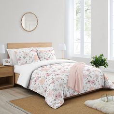 a bedroom with white walls and flooring has a large bed covered in pink flowers