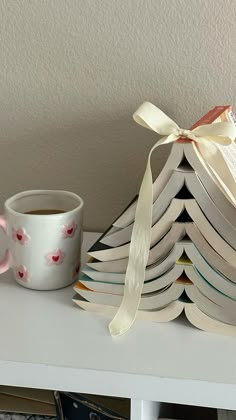 a stack of books sitting on top of a white table next to a cup of coffee