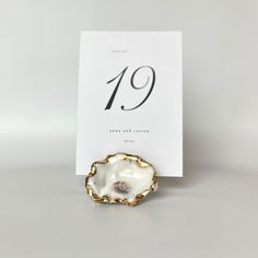 a white and gold brooch sitting on top of a table next to a card