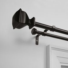 a close up of a curtain rod on a white wall with an open door in the background