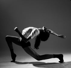 a woman is dancing on the floor in black and white