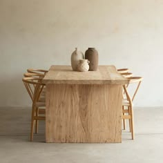 two vases sitting on top of a wooden table next to chairs and a wall