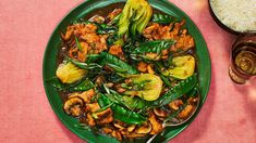 a green plate filled with meat and vegetables next to rice on a pink tablecloth