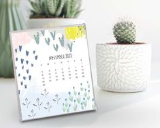 a calendar sitting on top of a table next to a potted cactus