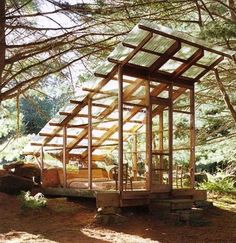 a small wooden structure sitting in the middle of a forest next to a truck and trees