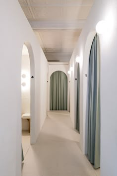 an empty hallway with arched doorways and curtains