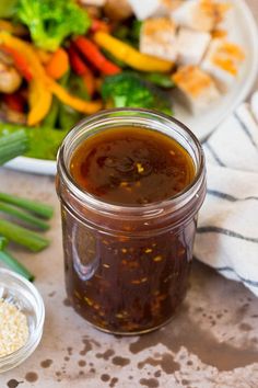 a jar of barbecue sauce next to a plate of vegetables