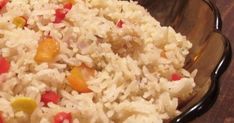 a bowl filled with rice and vegetables on top of a wooden table