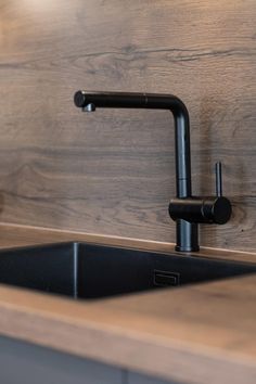 a black faucet on the side of a kitchen sink next to a wooden counter top