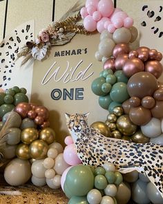 a leopard balloon wall with balloons and a sign that says wild one on the front