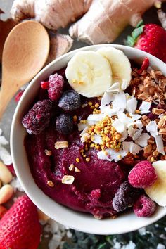 a bowl filled with fruit and nuts on top of a table next to sliced bananas