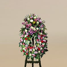 an arrangement of flowers is displayed on a stand