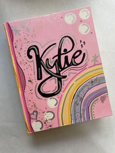 a pink notebook with the word kydie written in cursive writing on it