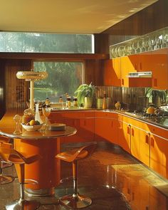 an orange kitchen with lots of counter space and stools around the dining room table