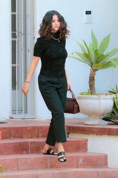 a woman in black is walking up some steps