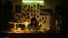 a woman sitting at a desk in front of a lamp